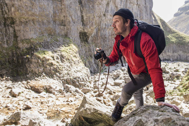 Mountaineer climbing over rocks and taking photographs — Stock Photo
