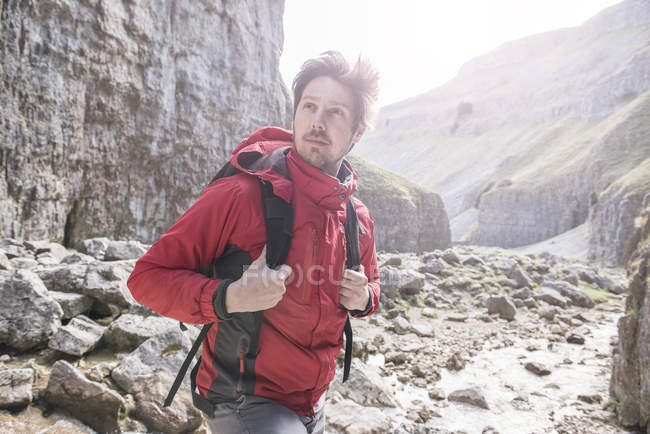 Climber with rucksack standing in rugged terrain — Stock Photo