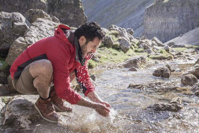 Alpiniste s'arrêtant pour se laver dans le ruisseau de montagne — Photo de stock