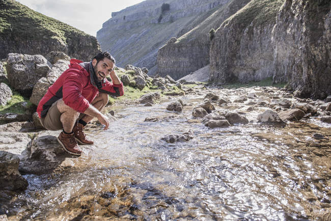 Bergsteiger hält an, um sich in Gebirgsbach zu waschen — Stockfoto