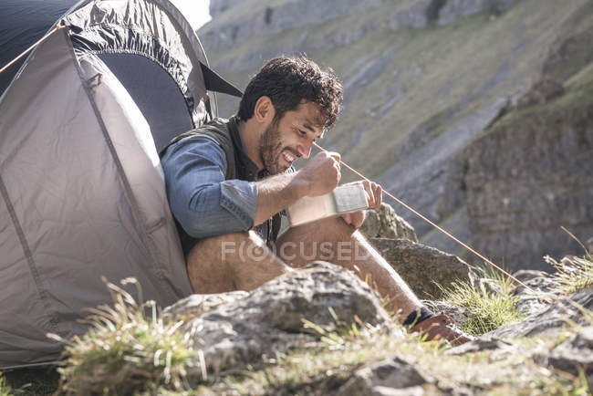 Montañista comiendo comida en campamento base - foto de stock