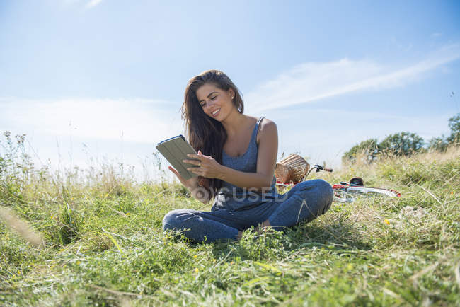 Жінка читає книгу під час сидіння на лузі — стокове фото