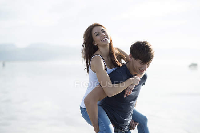 Homme donnant piggyback tour à un ami féminin — Photo de stock