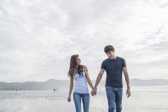 Пара прогулянка тримає руки через пляж — стокове фото