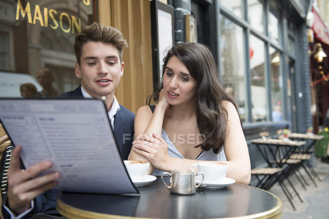 Paar schaut sich Speisekarte vor Café an — Stockfoto