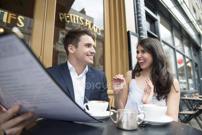 Paar schaut sich Speisekarte vor Café an — Stockfoto
