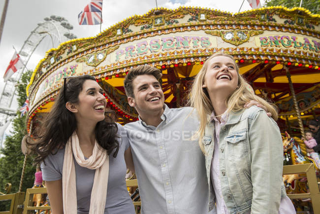 Friends standing in front of carousel — Stock Photo