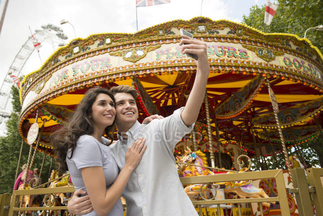 Casal tomando selfie na frente do carrossel — Fotografia de Stock
