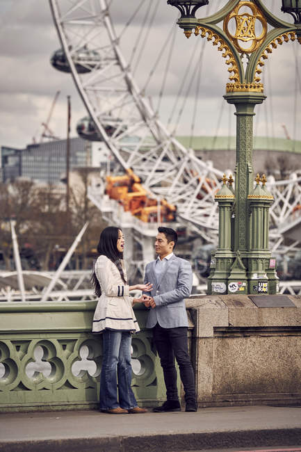 Пара говорить, стоячи на мосту — стокове фото