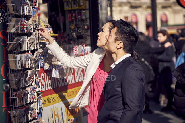 Couple choisir des cartes postales en stand — Photo de stock