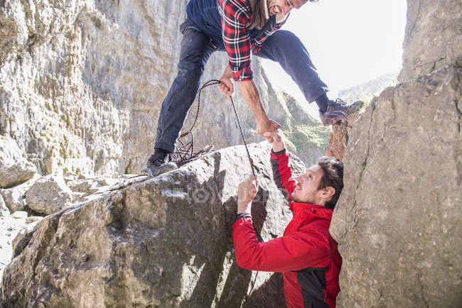 Dos montañeros ayudándose mutuamente - foto de stock