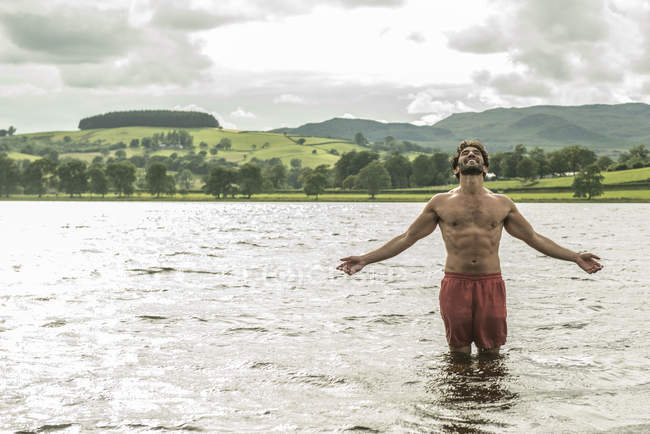 Mann steht mit ausgestreckten Armen im Wasser — Stockfoto