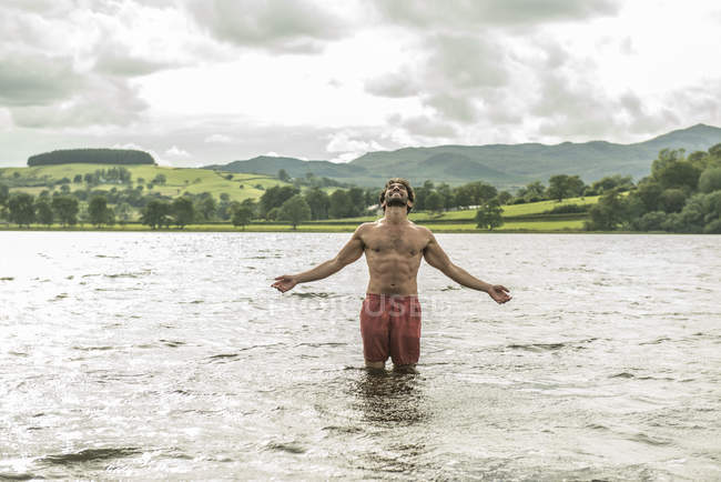 Homem de pé com os braços estendidos na água — Fotografia de Stock