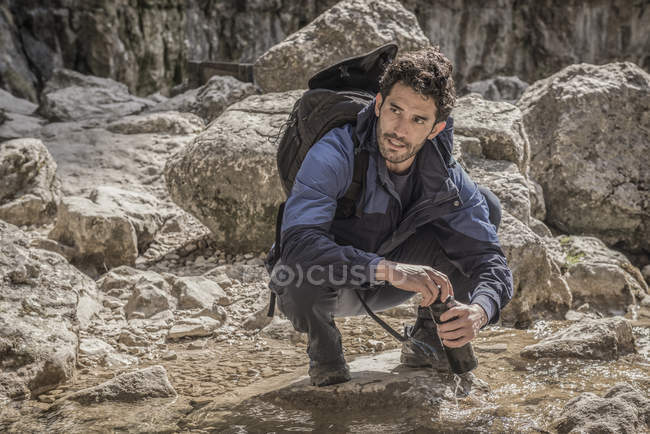 Bergsteiger füllt seine Wasserflasche — Stockfoto