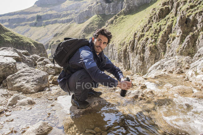 Alpinista riempiendo la sua bottiglia d'acqua — Foto stock