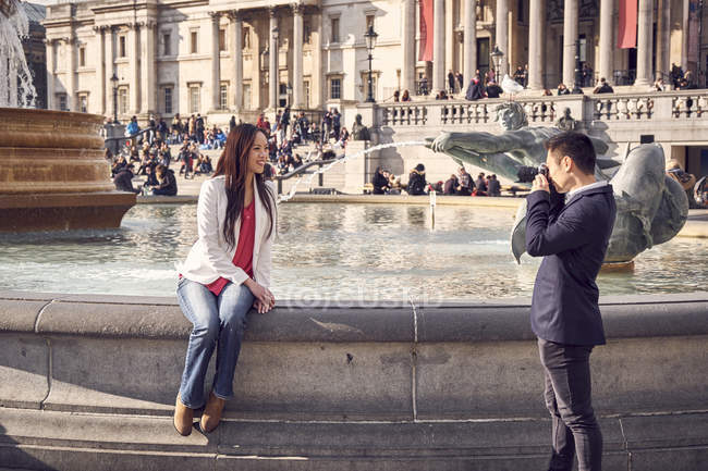 Donna sul bordo della fontana in posa per la fotocamera — Foto stock