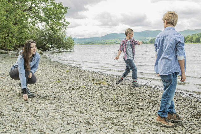 Frau und zwei Jungen spielen am Ufer — Stockfoto