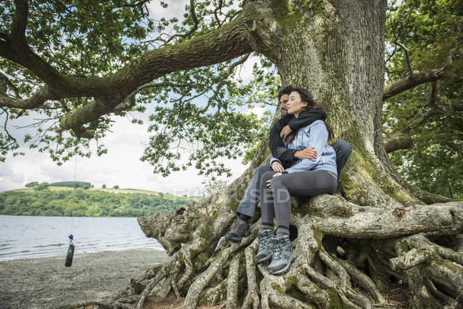 Lovers cuddling in tree on shore — Stock Photo
