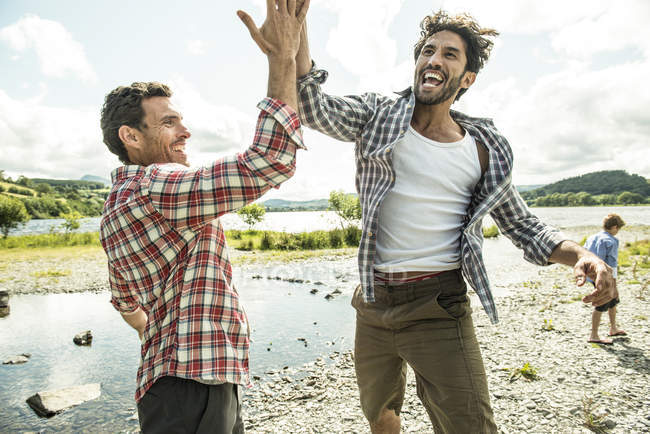 Men leaping to high five — Stock Photo