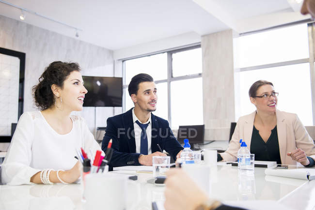Personas sentadas en un ambiente de oficina discutiendo - foto de stock