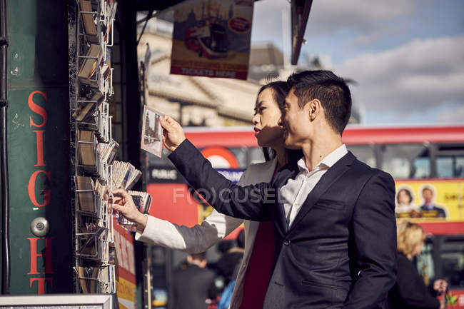 Coppia scegliere cartoline mentre in piedi sulla strada
. — Foto stock