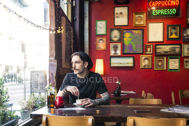 Homem sentado à mesa e olhando para a janela — Fotografia de Stock