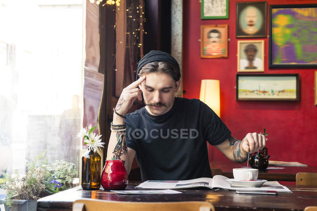 Человек сидит за столом и читает журнал — стоковое фото