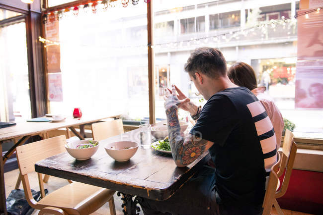 Coppia godendo pasto in caffetteria — Foto stock