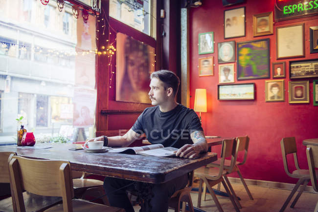 Homme assis à table et regardant la fenêtre — Photo de stock