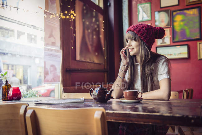 Woman sitting at table and talking on phone — Stock Photo