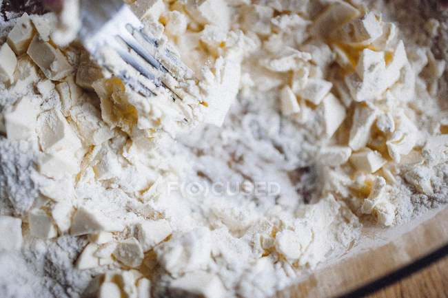 Fork mashing butter pieces in flour — Stock Photo