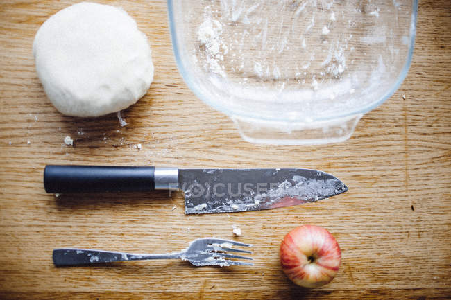 Dough with apple and cutlery — Stock Photo