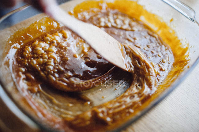 Hand stiring sauce in baking tray — Stock Photo