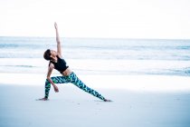 Woman doing yoga exercise on beach — Stock Photo
