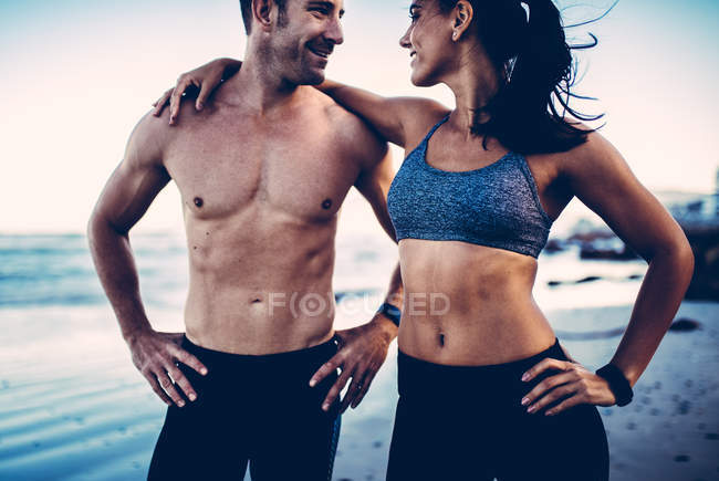 Casal atlético em pé na praia — Fotografia de Stock