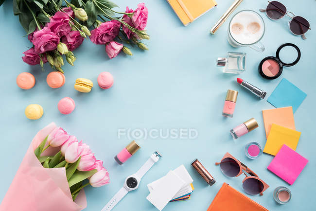 Flores con gafas de sol y cosméticos con macarrones - foto de stock