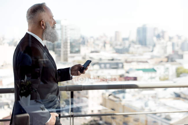 Бізнесмен використовує смартфон на балконі — стокове фото