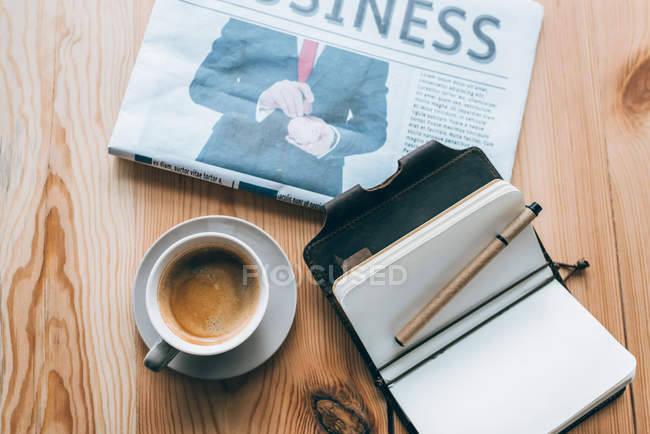 Xícara de café, jornal e caderno na mesa — Fotografia de Stock