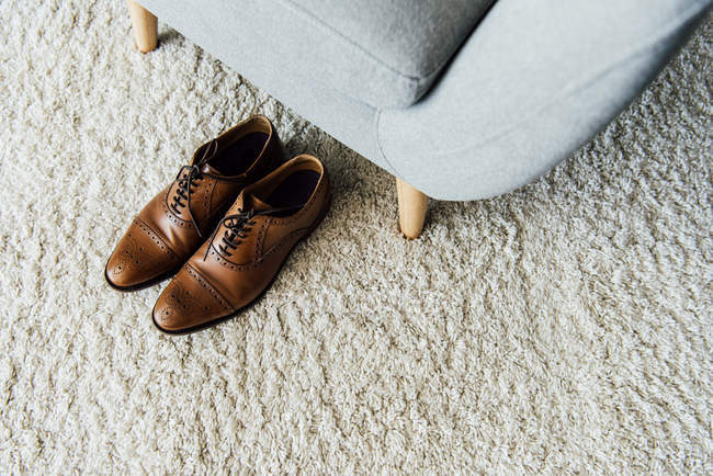 Oxford shoes on carpet near armchair — Stock Photo