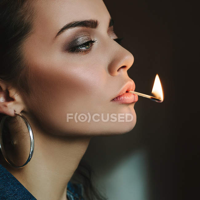 Woman with perfect skin holding her lips with a match flame — Stock Photo