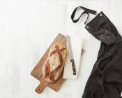 Fresh bread, knife on paper bag — Stock Photo