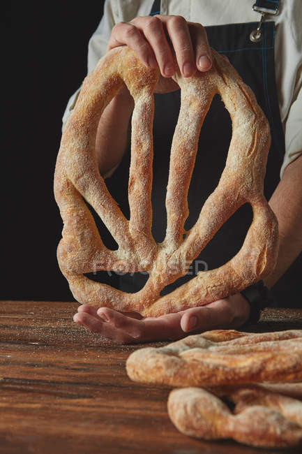 Baker holding loaf of  bread — Stock Photo