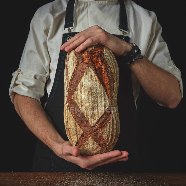 Baker holding loaf of  bread — Stock Photo