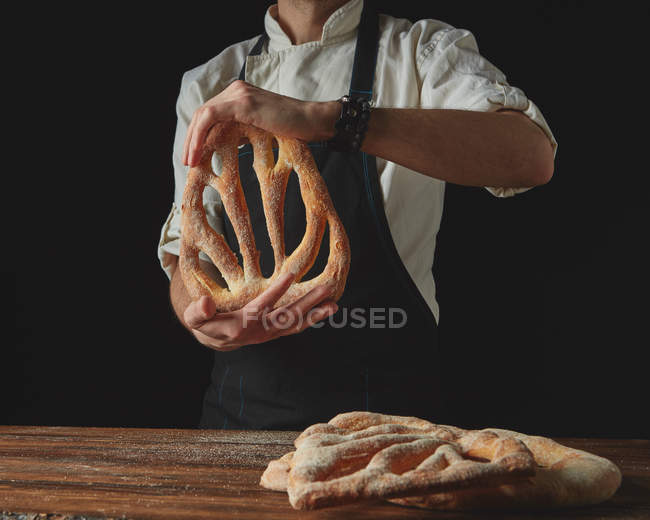 Пекарь держит буханку хлеба — стоковое фото