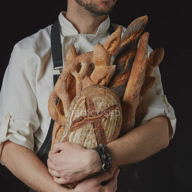 Boulanger avec différents pains — Photo de stock