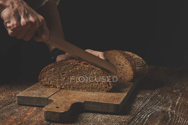 Bäcker schneidet Brot — Stockfoto