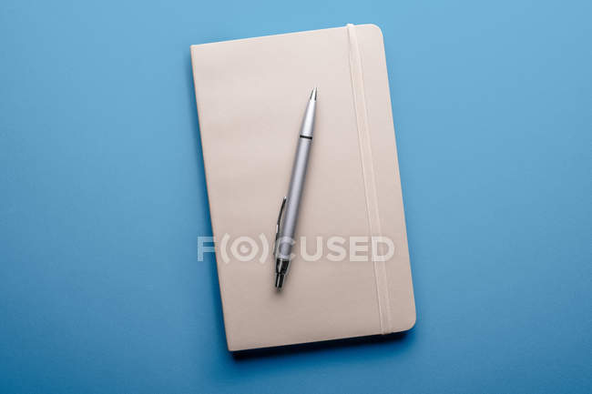 Vista superior do notebook em branco com caneta sobre fundo azul — Fotografia de Stock