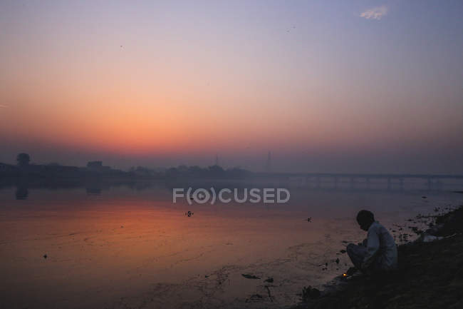 Uomo seduto sulla riva — Foto stock