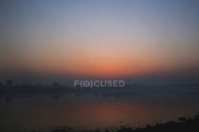 Rivière au coucher du soleil avec lumière orange — Photo de stock