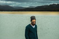Uomo in pullover in piedi sulla riva del mare — Foto stock